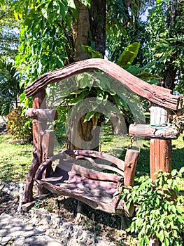 Wooden swing in the green tree gardent, log