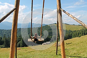 Wooden Swing on Mountain Meadow: A Serene Retreat with Majestic Mountain View and Lush Pine Forest. Enjoy a Sunny Summer Day as a