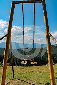 Wooden Swing on Mountain Meadow: A Serene Retreat with Majestic Mountain View and Lush Pine Forest. Enjoy a Sunny Summer Day as a