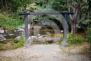 Wooden swing set beside a stream and relaxing atmosphere.