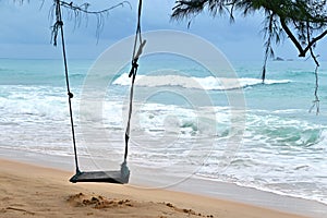 A wooden swing on the tropical island beach under beautiful blue sea and sky, Phuket, Thailand