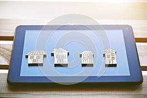 Wooden symbols of houses on digital tablet computer