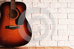 Wooden table with an acoustic guitar and white bricks background