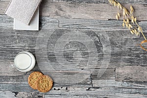 Wooden table background, milk, cookies, oats, notebooks. Copy space