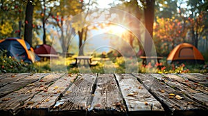 A wooden table with a beautiful blurred background of a campsite in the woods with a warm sunlight shining through the trees