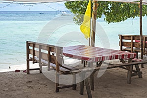 A wooden table and bench with a linoleum covered top right by the beachfront. At Libaong Beach, Panglao, Bohol, Philippines