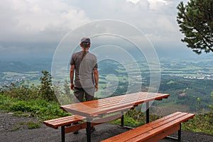 Wooden table and benches, hiker with dreadlocks and view from Velky Javornik to Frenstat nad Radhostem, Beskid Mountains