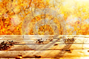 Wooden table and blurred Autumn background. Autumn concept with red-yellow leaves background. Autumn mock-up.