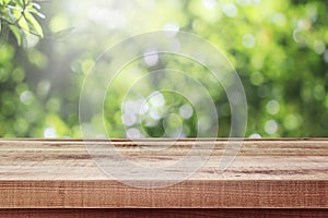 Wooden table and blurred fresh garden nature bokeh background.