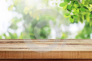 Wooden table and blurred green leaves in garden nature background.