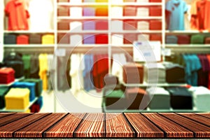 Wooden table with blurry background of casual boutique shop, shirt brand outlet or colorful clothes store for product display