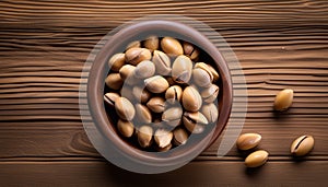 A wooden table with a bowl of peanuts and some peanuts scattered around it