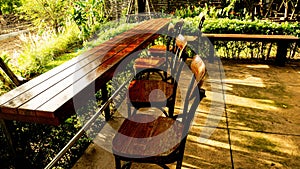 Wooden Table and Chair on Wood Deck in the Garden with Sunset on nature field grass flower background