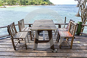 Wooden table and chairs in empty beach cafe next to sea water. Island Koh Phangan, Thailand