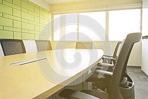 Wooden table and chairs in a meeting room with sound absorbing wall sunlight through windows