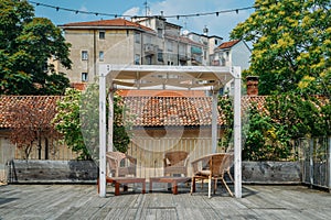 Wooden table and chairs on an outdoor terrace in a residential neighbourhood during the summer.