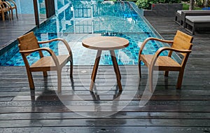 Wooden table and chairs at the poolside for breakfast in luxury hotel