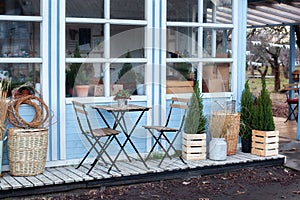 Wooden table and chairs on veranda of house. Exterior street cafe with furnuture. Outdoor home decor. Facade Terrace with wicker b