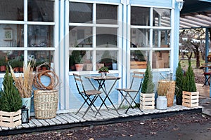 Wooden table and chairs on veranda of house. Exterior street cafe with furnuture. Outdoor home decor. Facade Terrace with wicker b