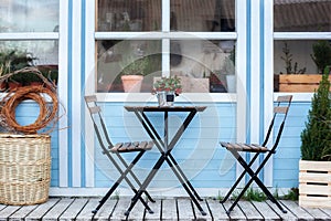 Wooden table and chairs on veranda of house. terrace with baskets and green plants