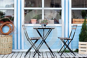 Wooden table and chairs on veranda of house. there is potted Christmas mistletoe on table in street cafe. Outdoor home decor. terr