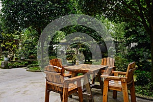 Wooden table and chairs in verdant yard on summer day