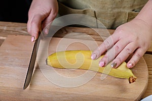 On a wooden table on a cutting board, a woman cooked a banana to make a fruit cocktai