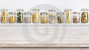 Wooden table on defocused background of groceries in glass jars