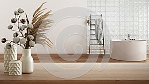 Wooden table, desk or shelf close up with ceramic vases with cotton flowers over minimal bathroom with glass brick wall,