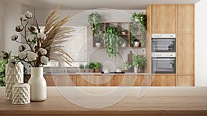Wooden table, desk or shelf close up with ceramic vases with cotton flowers over modern kitchen with houseplants, urban jungle