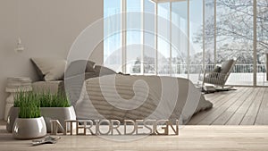 Wooden table, desk or shelf with potted grass plant, house keys and 3D letters making the words interior design, over blurred bedr