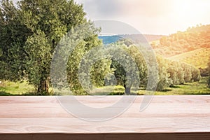 Wooden table for display montages with olive trees on background