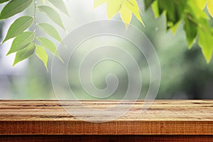 Wooden table and empty blurred green leaves nature background for product.