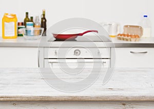 Wooden table in focus over blurred baking ingredients on kitchen