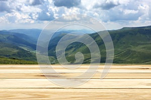 Wooden table, free space, your product or advertising text, green mountain valley, blue sky and clouds, light colors, kopi space,