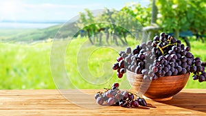 Wooden table with fresh red grapes and free space on nature blurred background, vineyard field. Generated AI.