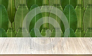 A wooden table in front, the background is a green banana leaf arranged like a wall