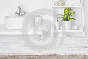 Wooden table in front of blurred white bathroom shelves background