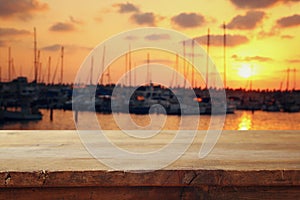 wooden table in front of blurred yachts in pier at sunset