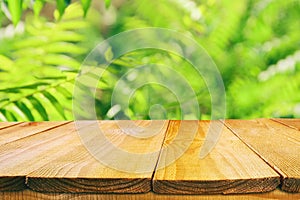 wooden table in front of tropical green floral background. for product display and presentation.