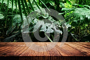 wooden table in front of tropical green floral background. for product display and presentation