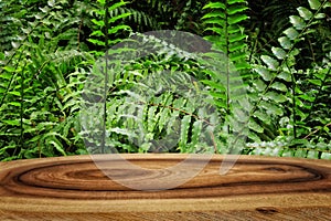 wooden table in front of tropical green floral background. for product display and presentation