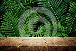 wooden table in front of tropical green floral background. for product display and presentation