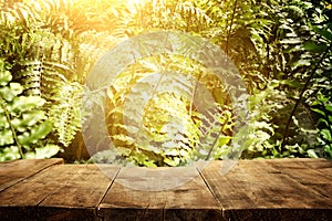 wooden table in front of tropical green floral background. for product display and presentation