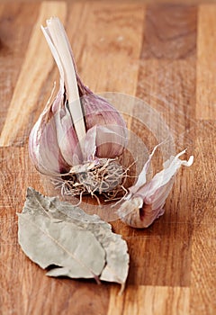 On the wooden table is garlic and bay leaf