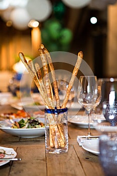 On a wooden table in a glass glass there are Grissini Italian breadsticks. Beautifully sealed table