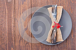 Wooden table with gray plate and fork and knife with autumn decoration, horizontal, top view, copy space