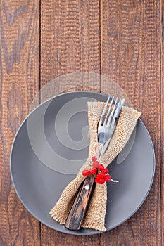 Wooden table with gray plate and fork and knife with autumn decoration, vertical, top view, copy space