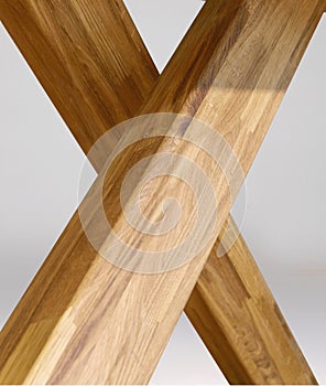 Wooden table legs isolated over gray background, close view photo, crossed star shaped legs, wooden eco furniture elements