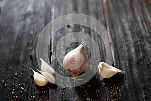 On the wooden table lies organic antioxidant garlic next to spices